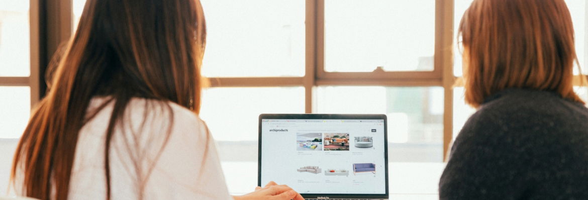 two women talking while looking at laptop computer