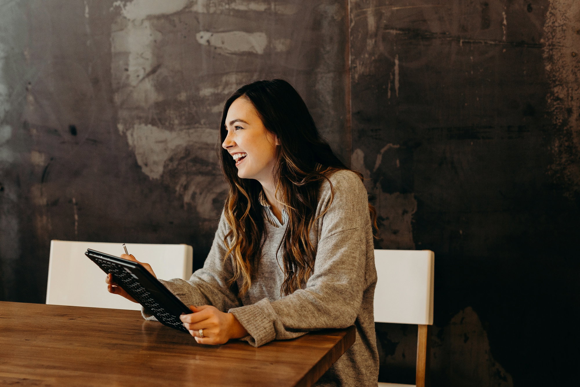 woman-sitting-around-table-holding-tablet.jpg woman sitting around table holding tablet